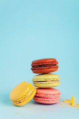 Colorful cake macaron or macaroon with crumbs on blue pastel background. Different types of macaroons. Colorful almond cookies, pastel colors, vintage card, copy space for text.