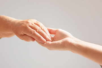 Helping hands on grey background, closeup. Elderly care concept