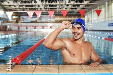 Young athletic man wearing cap and goggles in swimming pool