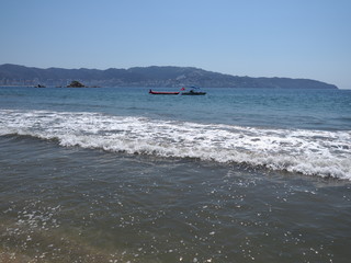 Beauty landscape of sandy beach at bay of ACAPULCO city in Mexico with motor boat and white waves...