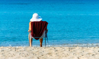 woman with white hat sitting on the beach