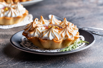 Grapefruit Tartlets with meringue and rosemary on black plate. Dark background. 