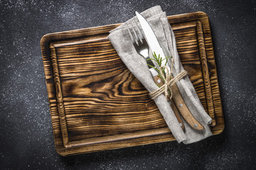 Wooden plate and cutlery on stone table top view.