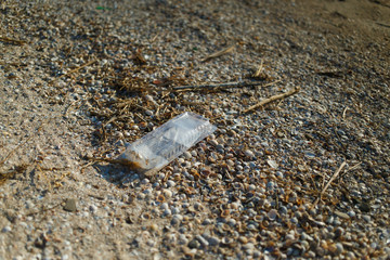 Garbage left by people on the beach. Garbage in public places. Environmental pollution. Plastic and glass on the beach.