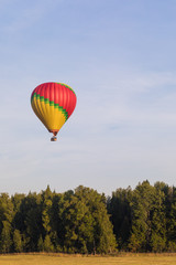 Colorful hot-air balloon flying over the forest