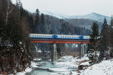 Dramatic railway above the mountain river winter Carpathians, Ukraine.