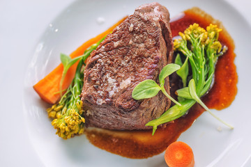beef steak with sauce and vegetables, served with sweet potatoes fries and glass of wine, product photography for restaurant and gastronomy