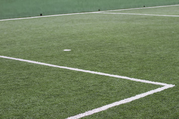 Soccer field with artificial grass, lines to mark the lawn and selective focus on part of the grass