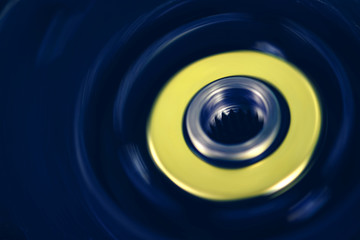 Blue and yellow device made of plastic with rotated metal gear. Vivid grunge mechanism with copy space. Background from retro device close up.
