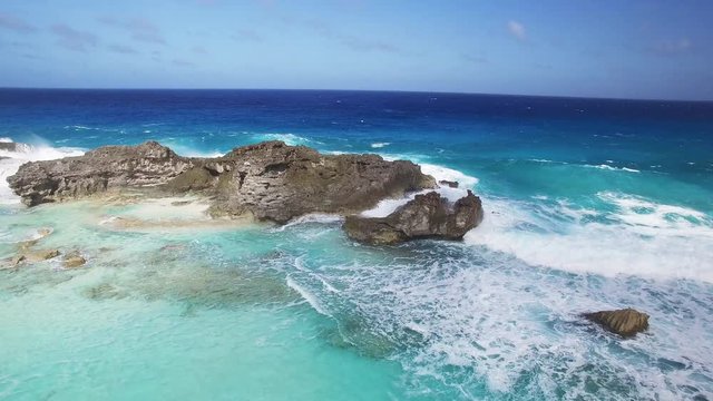 Pan left aerial, waves crash on rocks in Turks and Caicos