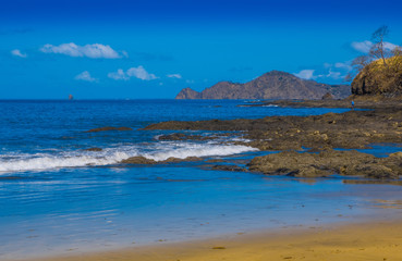 Beautiful outdoor view of of gorgeous rocky beach in Playa hermosa with blue water and beautiful sunny day with blue sky