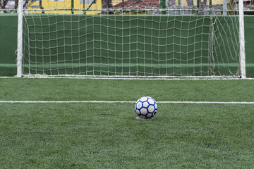 Soccer field with artificial grass, ball in the grass and lines to mark the lawn