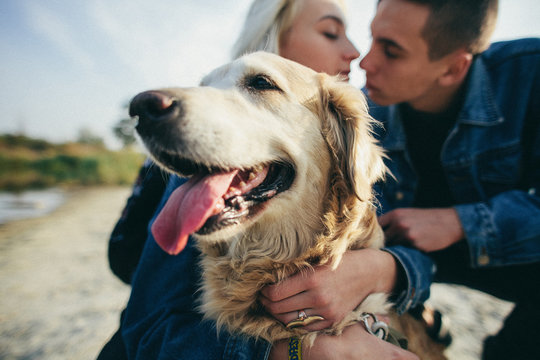 Beautiful romantic couple is having fun with their dog labrador retriever outdoors