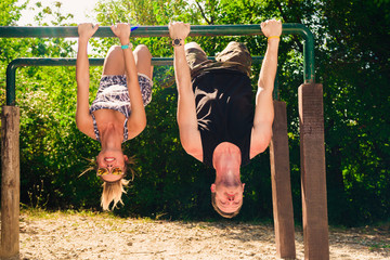 Couple doing exercises on high bars in forest gym