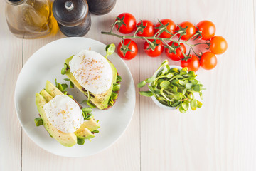 Avocado toast, cherry tomato and poached eggs on wooden background. Breakfast with vegetarian food, healthy diet concept.