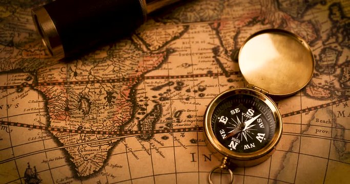 compass and spyglass on ancient world map
