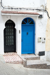 A traditional wooden blue door with an arc of a house with white walls, Tangiers Morocco