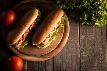 Photo of barbecue grilled hot dog with yellow mustard and ketchup on wooden background. Hot dog...