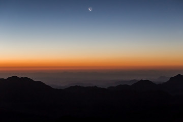 Majestic sunset in the mountains landscape and new moon. Dramatic scene. Gabal Musa, Horeb and Sinai Mountains, Egypt