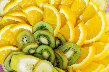 Pieces of orange and kiwi lie on a plate, close-up, top view.