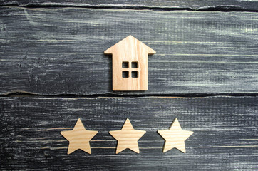 Wooden house and three stars on a gray background. Rating of houses and private property. Buying and selling, renting apartments. The level of the restaurant and hotels. Rating five stars.
