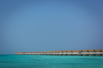 Plenty of bungalows over the blue water of Maldives in a clear sky day