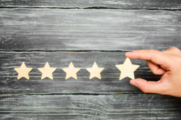 The businessman's hand in the suit holds the fifth star. Get the fifth star. The concept of the...