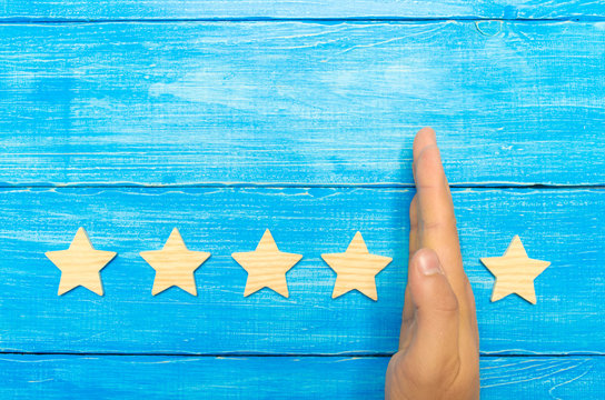 hand of the businessman separates the fifth star from the other four. loss of the fifth star, the fall in rating and recognition. critic takes the fifth star from a hotel, restaurant. selective focus