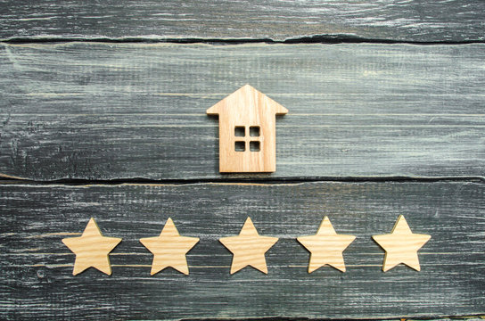 Wooden house and five stars on a gray background. Rating of houses and private property. Buying and selling, renting apartments. The level of the restaurant and hotels. Rating five stars.