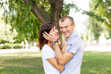 Obraz premium man and woman sitting on the lawn. in a white t-shirt and jeans. a walk in the Park. lover. young couple. summer. family. embrace 