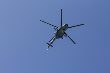 Naklejka na ściany i meble Military helicopter maneuvers in the blue sky