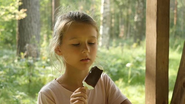 Charming child eats ice cream outdoors. Little girl licking ice-cream