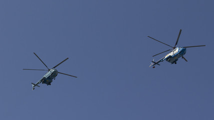 Fototapeta na wymiar Several military helicopters fly side by side against the blue sky