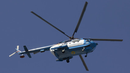 Military helicopter maneuvers in the blue sky