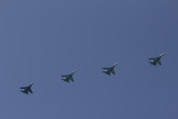 Naklejka na ściany i meble Several military fighters are flying in a formation against the blue sky