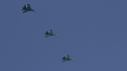 Several military fighters are flying in a formation against the blue sky