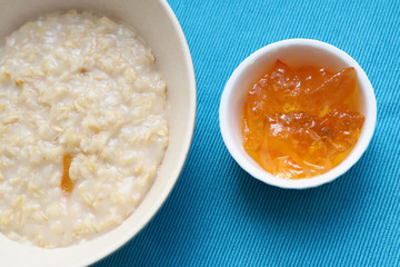 Porridge and orange jam or marmalade for morning breakfast on bright table