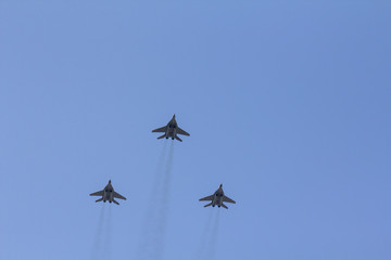 Several military fighters are flying in a formation against the blue sky