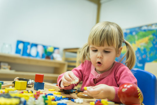 Little caucasian girl playing with wooden puzzle