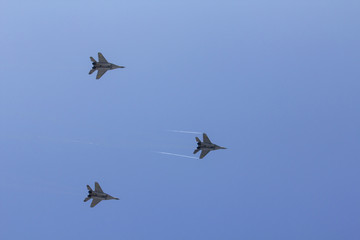 Several military fighters are flying in a formation against the blue sky