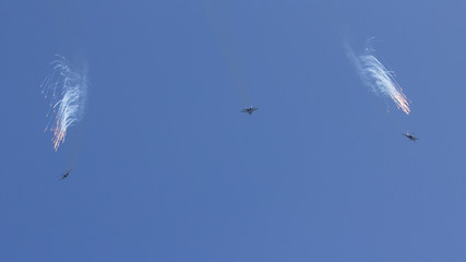 Several military fighters are flying in a formation against the blue sky