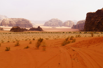 Fototapeta na wymiar Wadi Rum desert, Jordan, Middle East, known as The Valley of the Moon. Orange sand, blue sky, haze and clouds. Designation as a UNESCO World Heritage Site. Red planet Mars landscape.