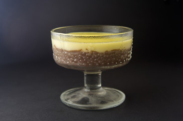 Mousse, souffle, pudding with vanilla and chocolate in glass black, dark background.