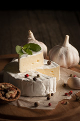 Camembert and brie cheese on wooden background with tomatoes, letuce and garlic. Italian food. Dairy products.