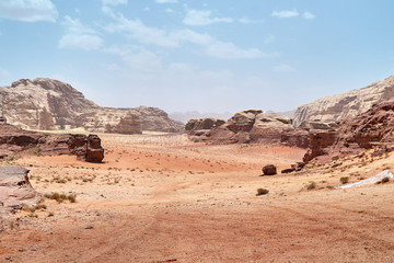 Fototapeta na wymiar Wadi Rum desert, Jordan, Middle East, The Valley of the Moon. Orange sand, haze, clouds. Designation as a UNESCO World Heritage Site. Red planet Mars landscape. Offroad adventures travel background.
