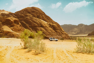 Safari jeep car in Wadi Rum desert, Jordan, Middle East, known as The Valley of the Moon. Sands, blue sky clouds. Designation as a UNESCO World Heritage Site.
