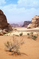 Wadi Rum desert, Jordan, Middle East, The Valley of the Moon. Orange sand, haze, clouds. Designation as a UNESCO World Heritage Site. Red planet Mars landscape. Offroad adventures travel background.