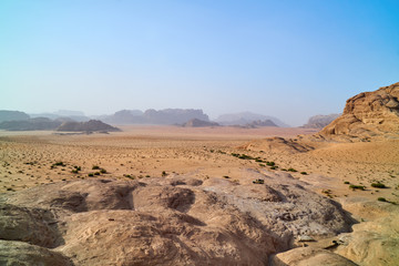 Wadi Rum desert, Jordan, Middle East, The Valley of the Moon. Orange sand, haze, clouds. Designation as a UNESCO World Heritage Site. Red planet Mars landscape. Offroad adventures travel background.