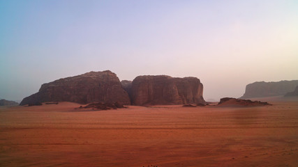                                Sunset time rocks in Wadi Rum desert (The Valley of the Moon). Jordan, Middle East.  Red sands, sky with haze. Designation as a UNESCO World Heritage Site.