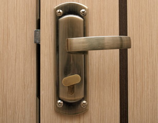 Obraz premium The metal door handle to open the beige door.
